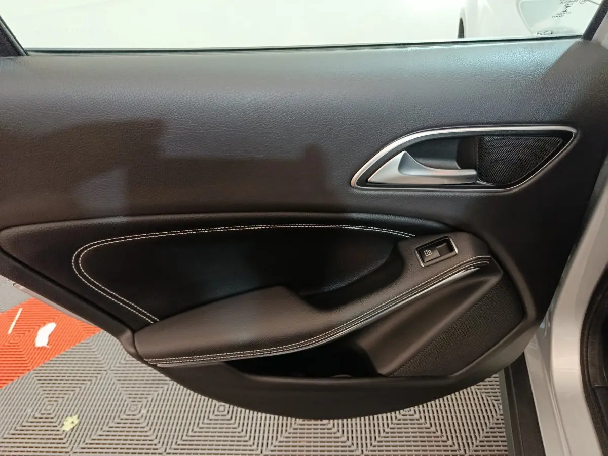 Gros plan sur la porte côté droit de la Mercedes GLA 200 d Business Executive gris clair, avec garniture noire et surpiqûres blanches.