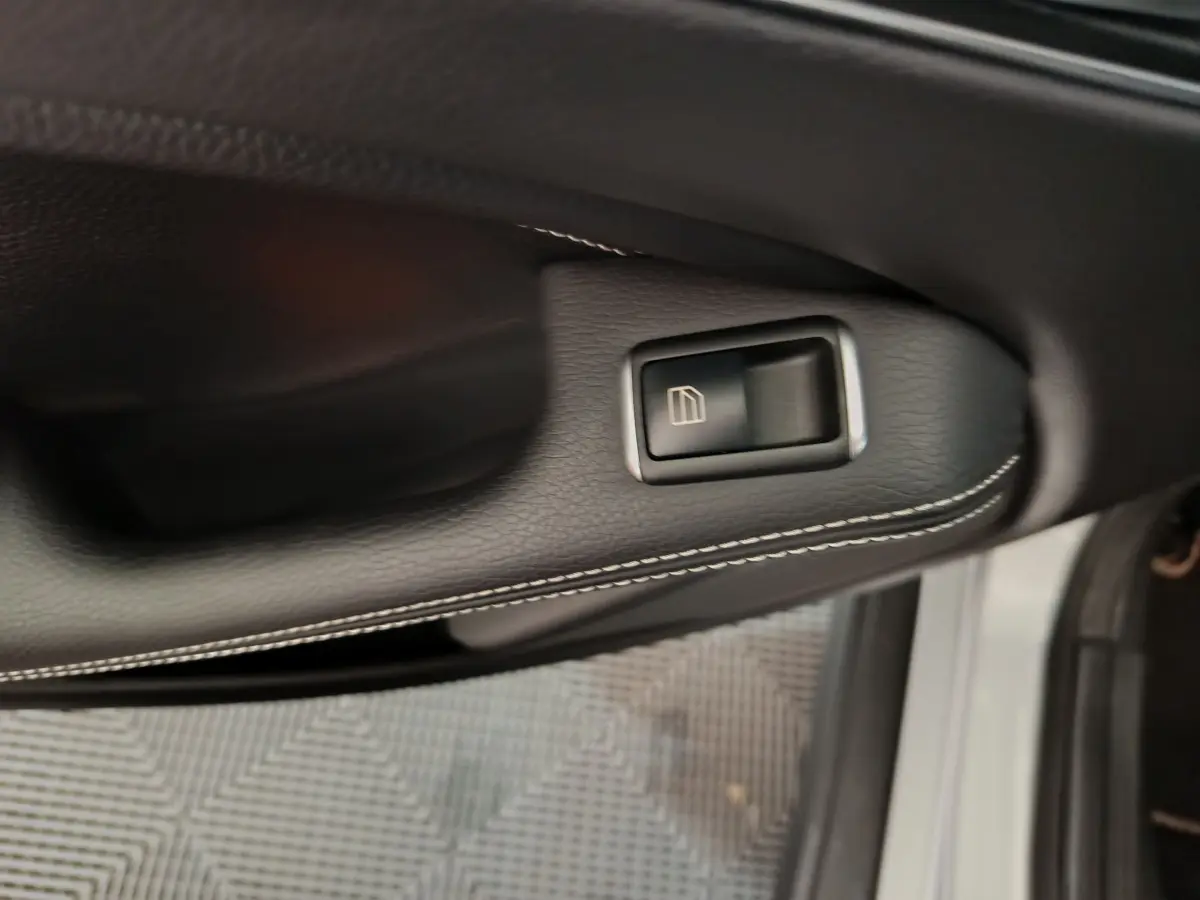 Bouton de commande de la vitre sur la porte côté conducteur d'un Mercedes GLA gris clair vu de près.