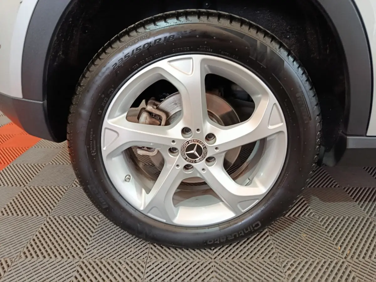 Gros plan sur la roue avant droite gris clair d'un Mercedes GLA 200 d avec jante alliage cinq branches et logo Mercedes central.