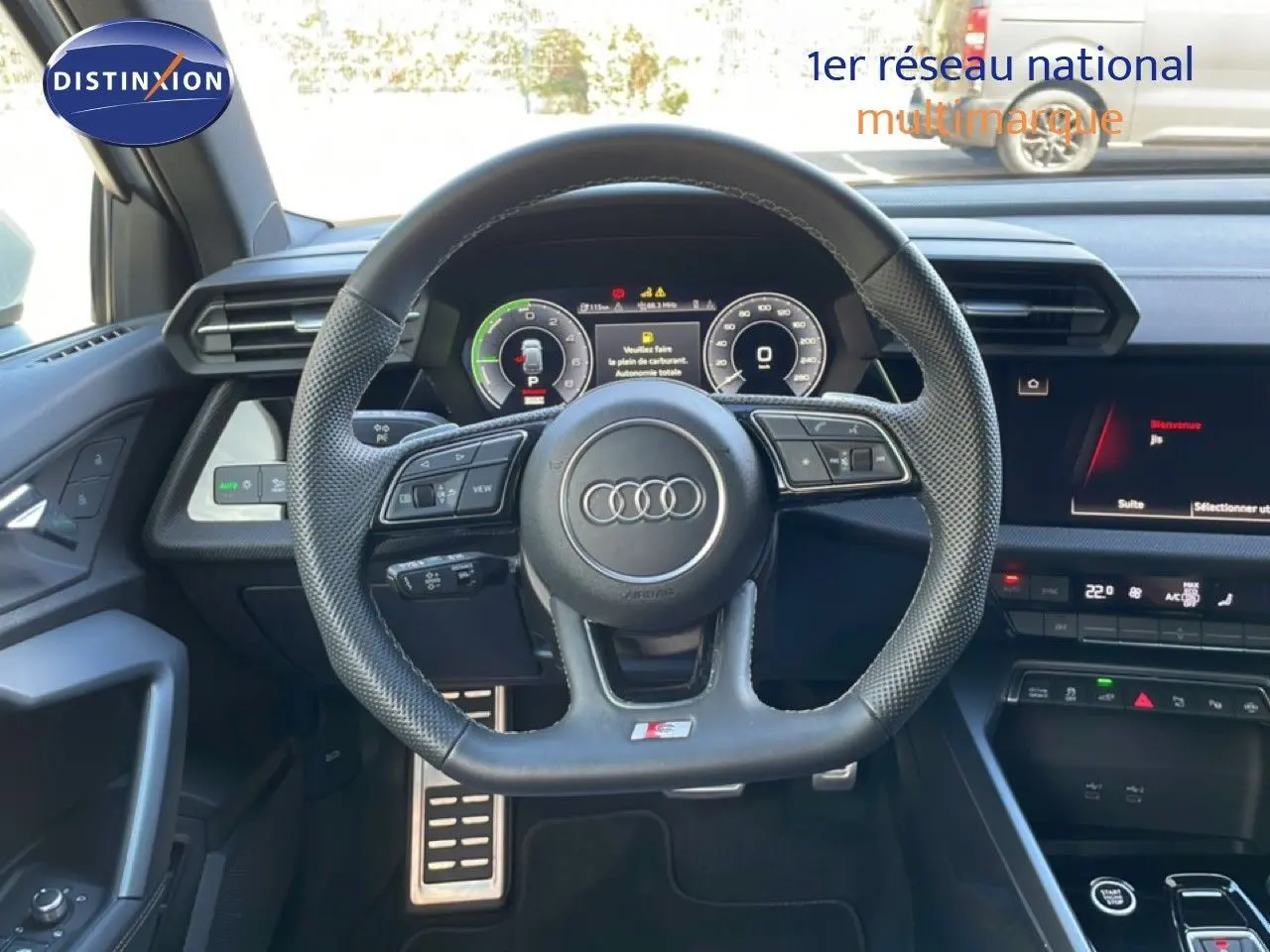Vue intérieure centrée sur le volant cuir perforé de l'Audi A3 Sportback 40 TFSIe avec tableau de bord digital et console moderne.