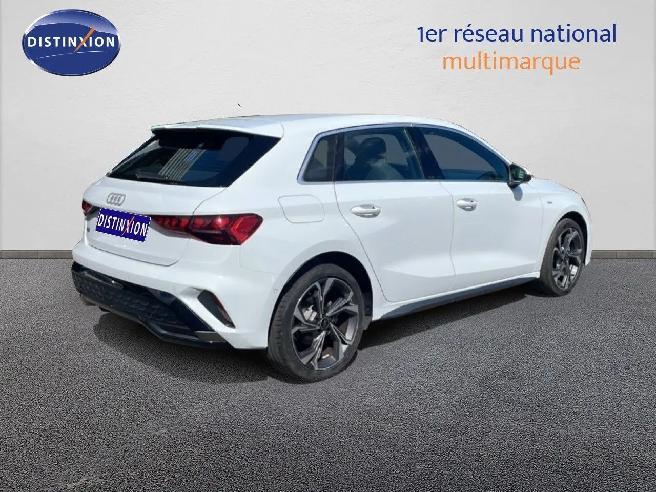 Audi A3 Sportback blanc Ibis vue 3/4 arrière droit, jantes alliage sombres et vitres teintées.