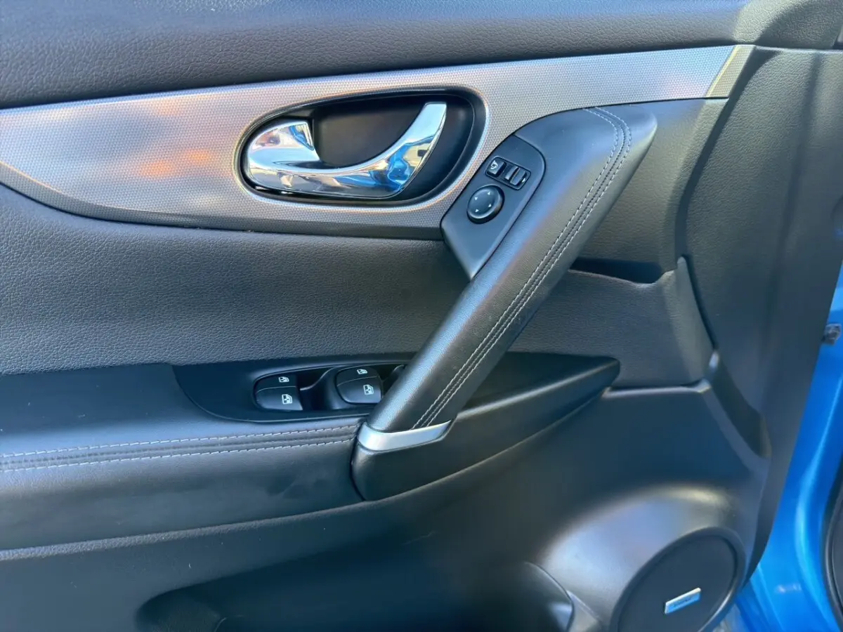 Détail de la porte avant gauche du Nissan Qashqai bleu 2018, avec poignée chrome et commandes électriques.