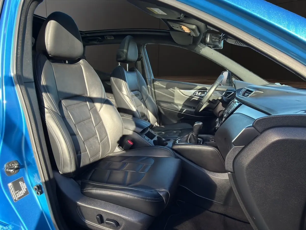 Vue intérieure côté gauche du Nissan Qashqai bleu 2018, mettant en valeur les sièges avant en cuir noir et le tableau de bord.