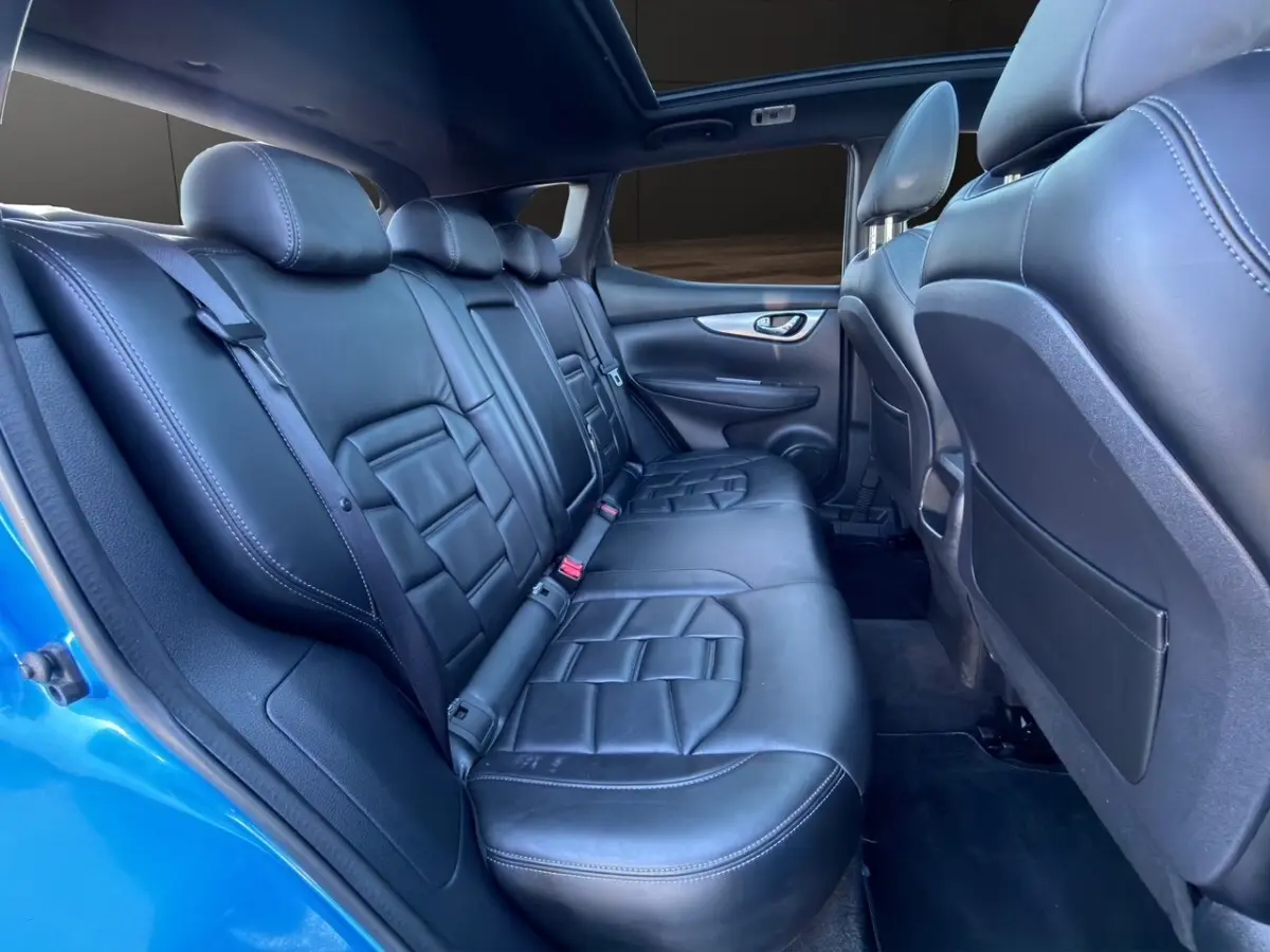 Vue intérieure côté droit des sièges arrière en cuir noir du Nissan Qashqai bleu 2018, avec appuie-têtes et ceintures visibles.