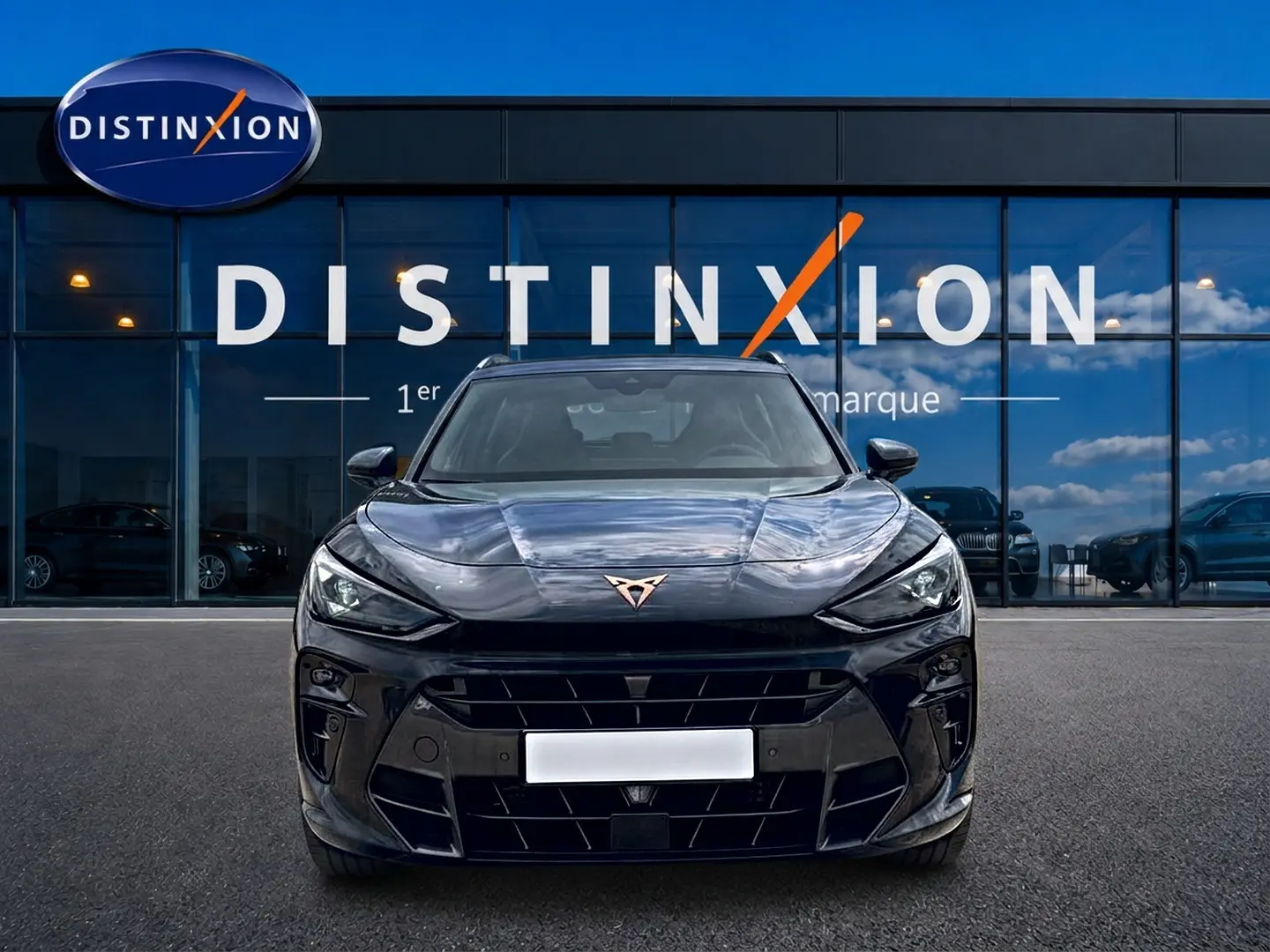 Vue frontale d'un CUPRA TERRAMAR gris timanfaya, avec logo cuivre et calandre large, devant une vitrine DISTINXION.