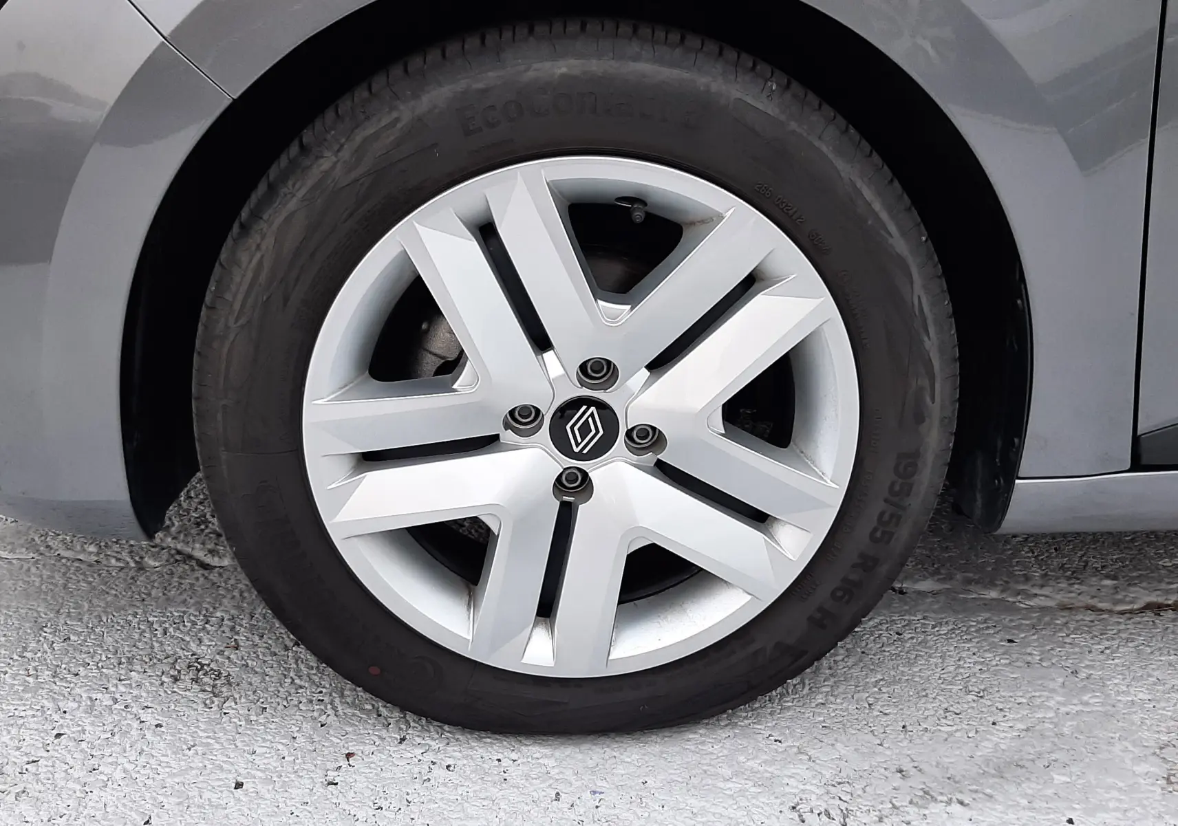 Gros plan sur la roue avant gauche d'une Renault Clio V gris schiste, jante alliage à cinq branches stylisées.