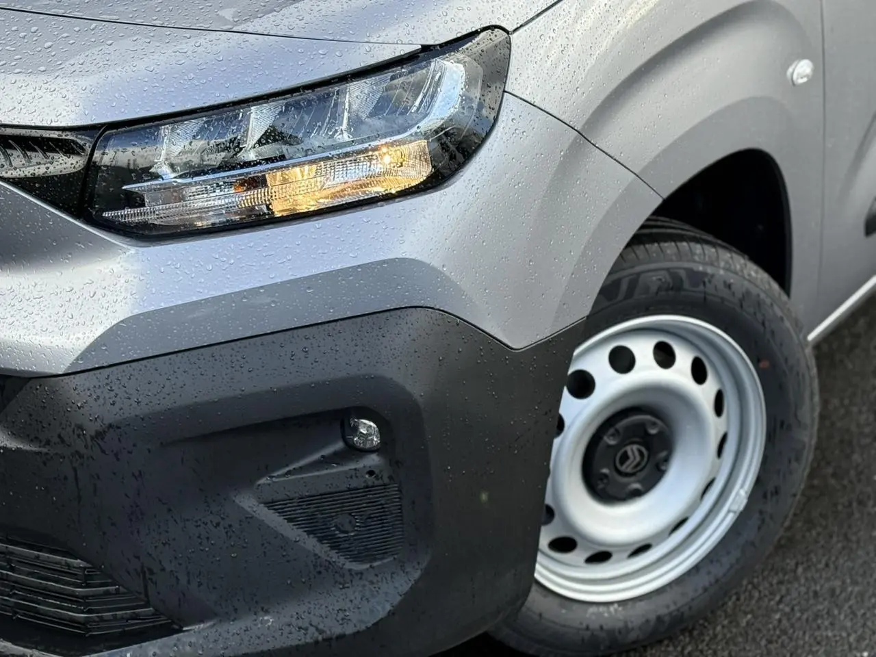 Gros plan sur l'avant droit gris Artense du Citroën Berlingo 2025 avec phare allumé et jante tôle 16 pouces.