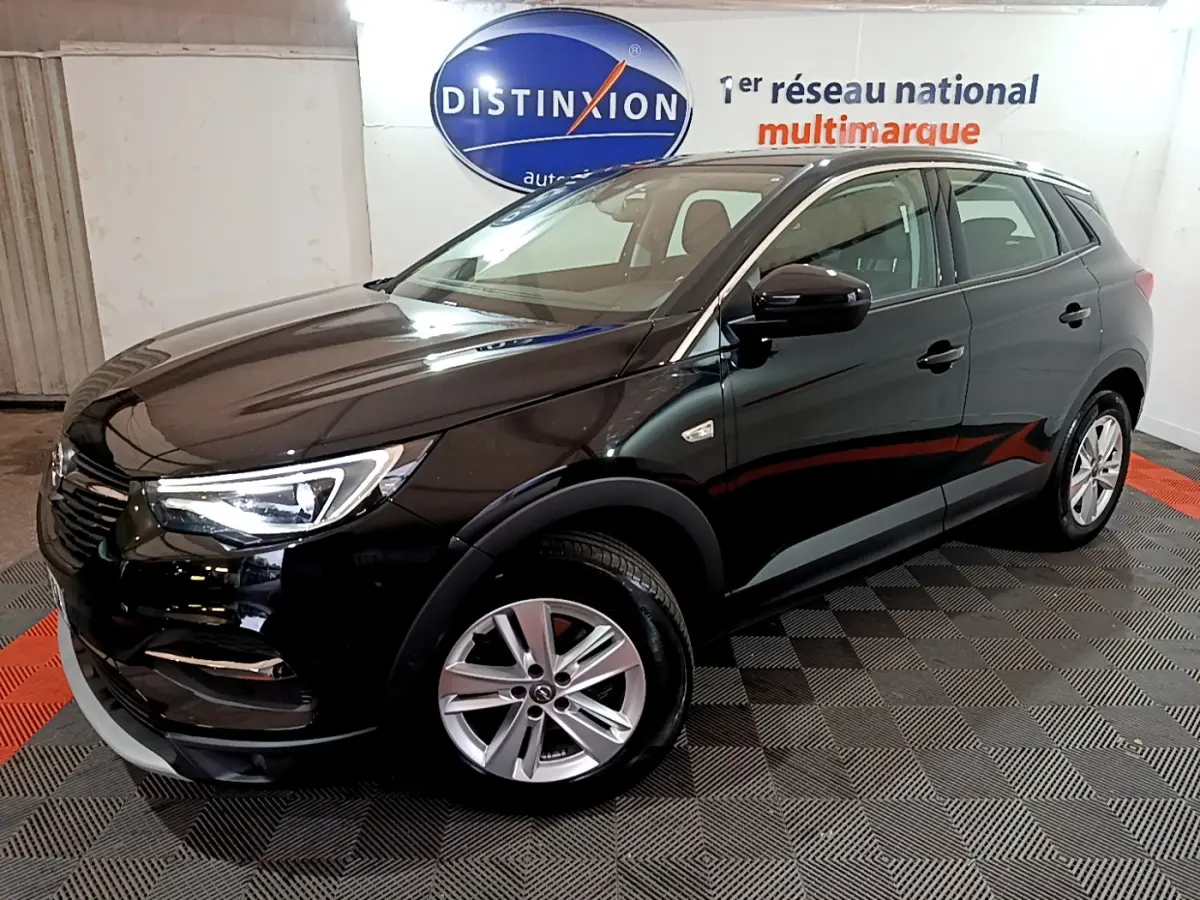Opel Grandland X noir vue 3/4 avant droit dans un showroom avec jantes alliage et phares LED allumés.