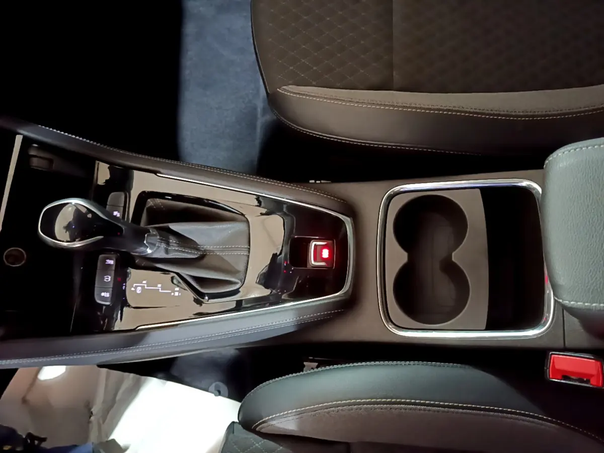 Vue plongeante sur la console centrale noire de l'Opel Grandland X 2021 avec levier de vitesse automatique et porte-gobelets.