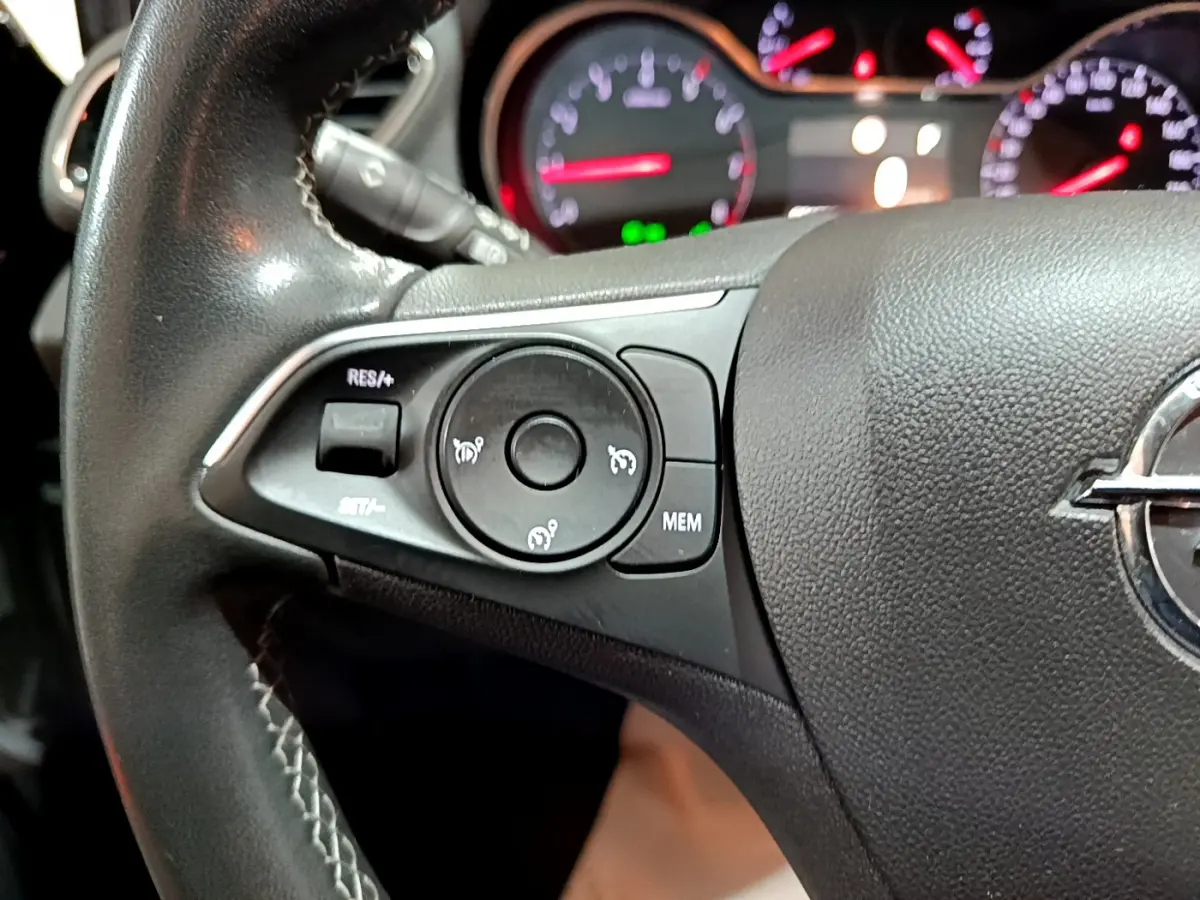 Gros plan sur le volant cuir noir de l'Opel Grandland X 2021 avec commandes de régulateur de vitesse et tableau de bord lumineux.