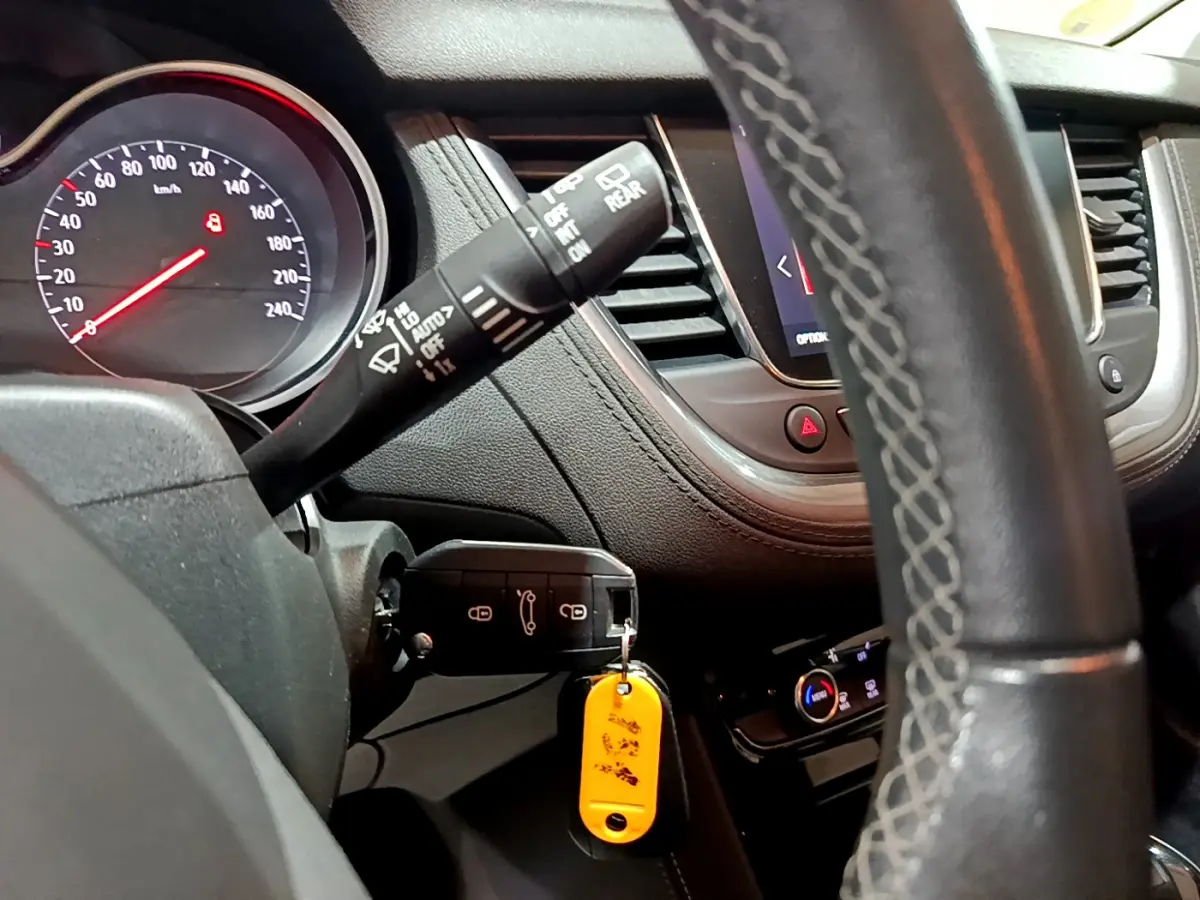 Vue rapprochée du tableau de bord noir de l'Opel Grandland X 2021, volant cuir et clé avec porte-clés jaune visible.