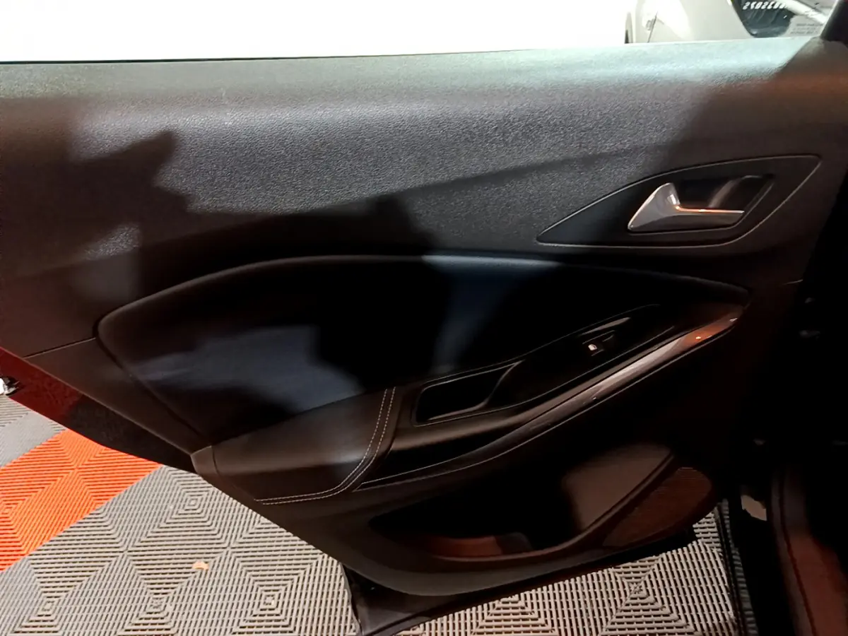 Gros plan sur la porte intérieure côté gauche de l’Opel Grandland X noir, avec poignée argentée et commande de vitre.