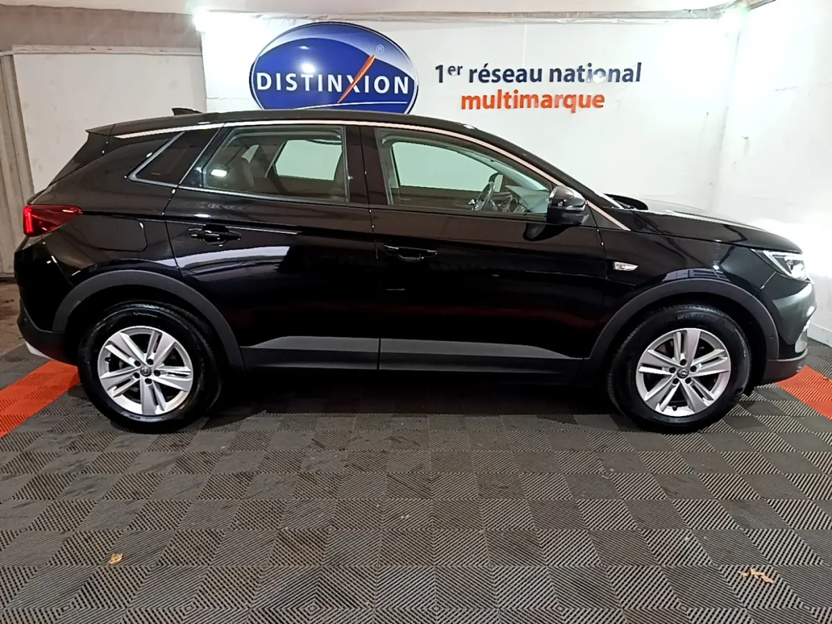 Opel Grandland X noir vue de profil côté gauche, dans un showroom avec logo Distinxion en arrière-plan.