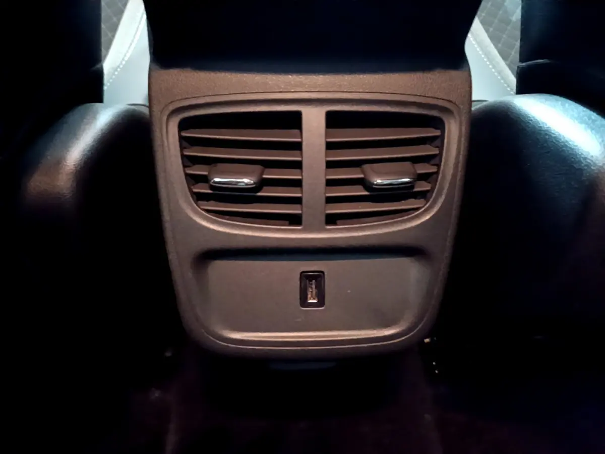 Prise USB et aérateurs arrière noirs du Opel Grandland X 1.5 Diesel 130 Elegance Business Auto, vue centrée du bas des sièges avant.