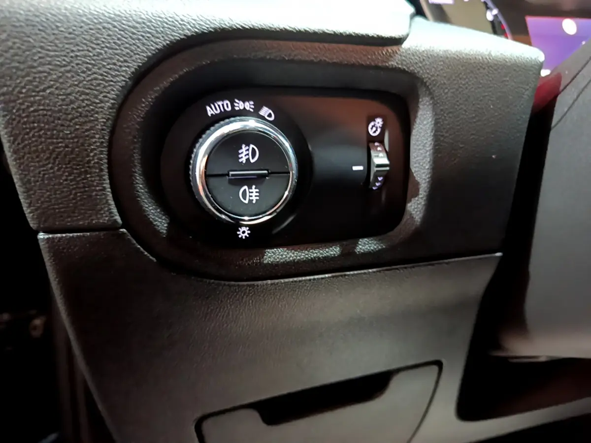 Gros plan sur le bouton de commande des phares noir dans l'habitacle de l'Opel Grandland X Diesel 2021.