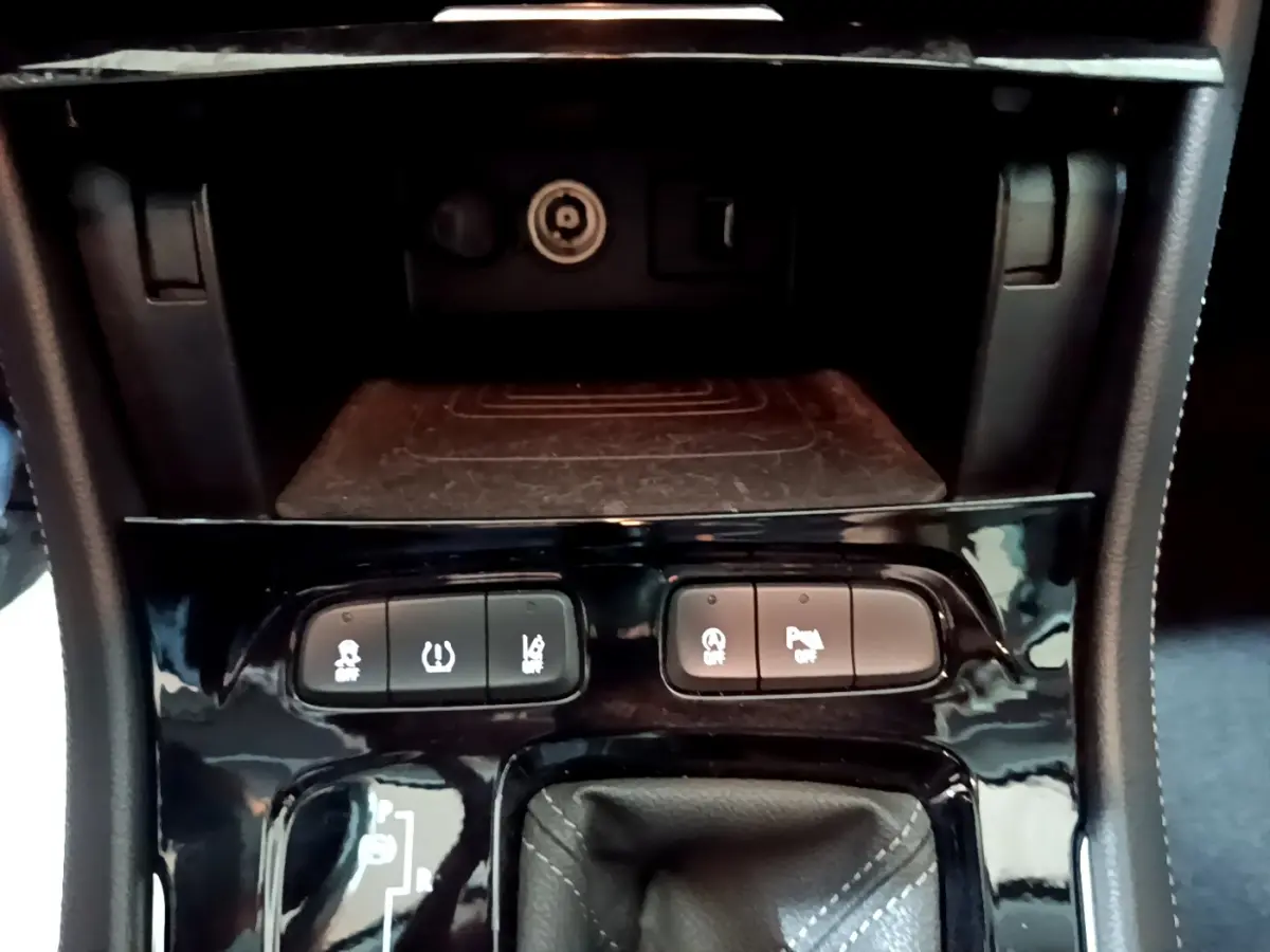 Gros plan sur la console centrale noire de l'Opel Grandland X 2021 avec boutons d'aide au stationnement et frein électrique.