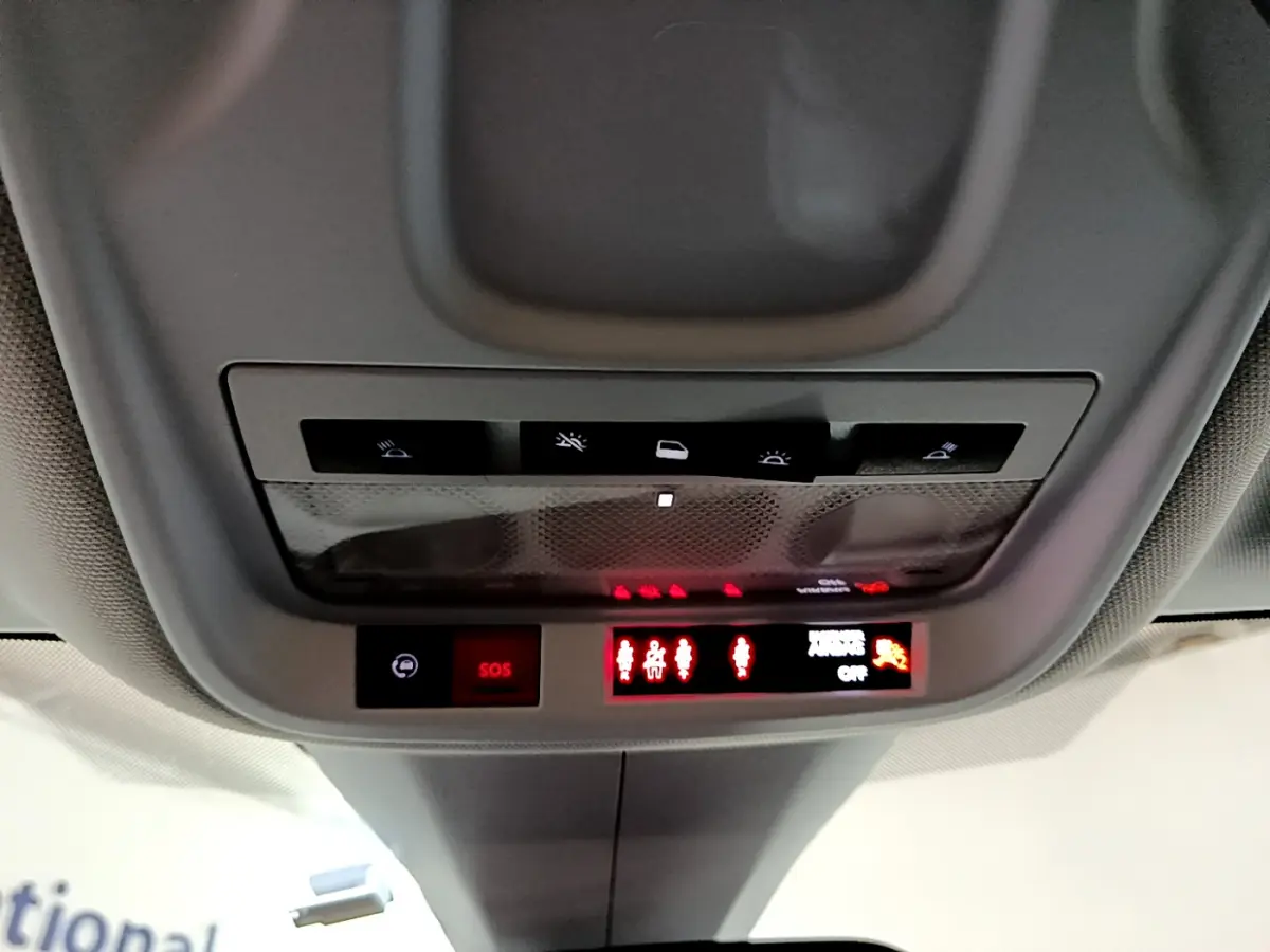 Vue en contre-plongée du panneau de commandes au plafond de l'Opel Grandland X noir, avec boutons SOS et éclairage intérieur.