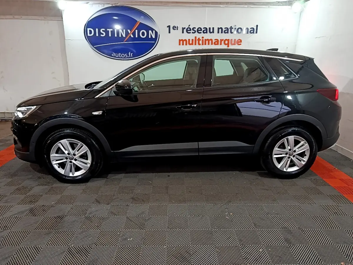 Opel Grandland X noir vu de profil côté gauche dans un garage avec logo Distinxion en arrière-plan.