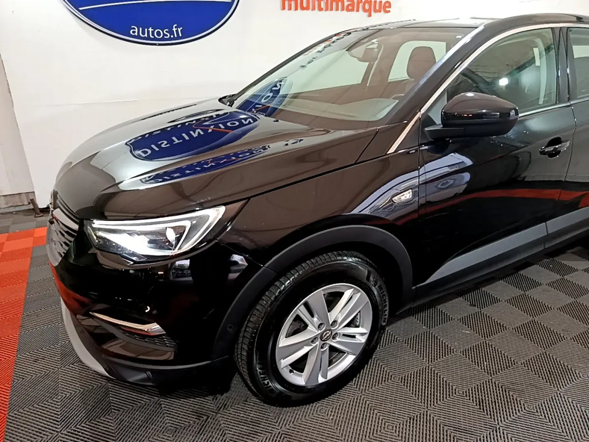 Vue 3/4 avant droit d'un Opel Grandland X noir brillant avec jantes alliage et phares LED allumés.