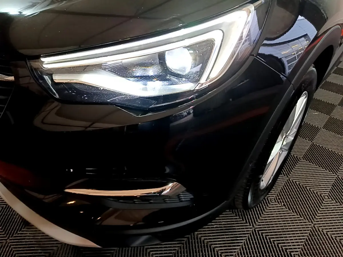 Gros plan sur le phare avant droit du SUV Opel Grandland X noir, mettant en valeur son design LED moderne.