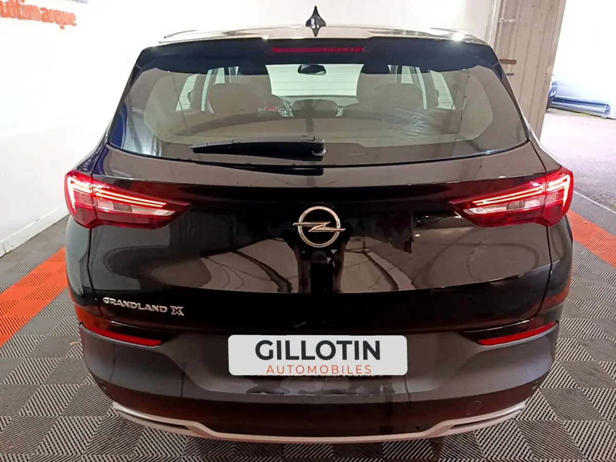 Vue arrière d'un Opel Grandland X noir avec feux LED allumés et logo Opel bien visible sur le coffre.