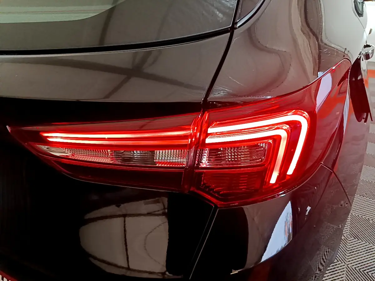 Gros plan sur le feu arrière droit rouge allumé d’un Opel Grandland X noir, reflétant l’environnement intérieur.