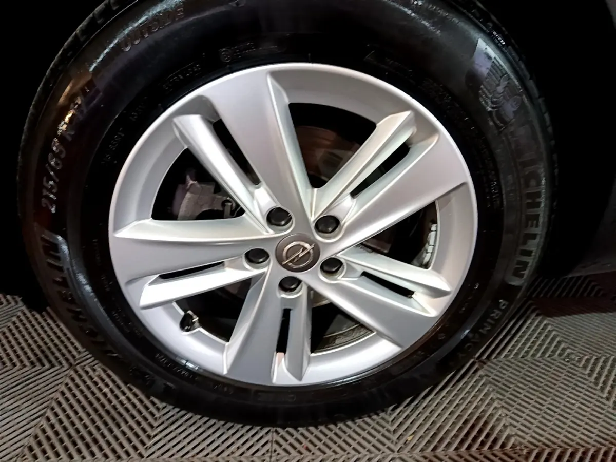Gros plan sur la jante argentée avec logo Opel d'un Grandland X noir, mettant en valeur le pneu Michelin.