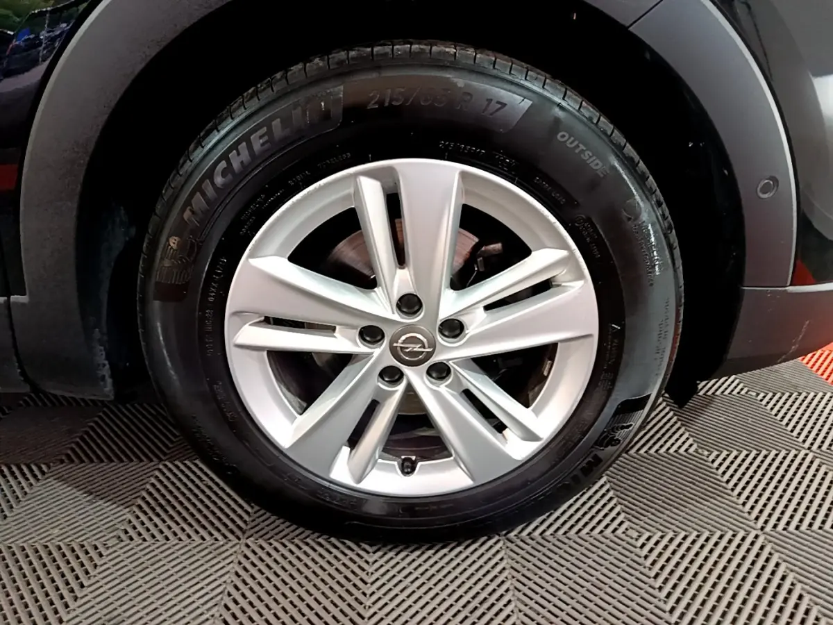 Gros plan sur la roue avant gauche noire de l'Opel Grandland X Diesel 2021 avec passage de roue gris anthracite.