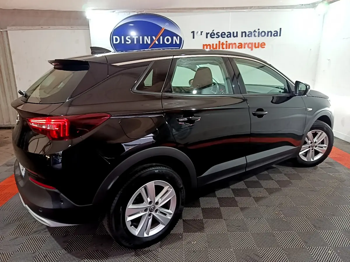 Opel Grandland X noir vue 3/4 arrière droit en intérieur, avec jantes alliage et feux arrière LED allumés.