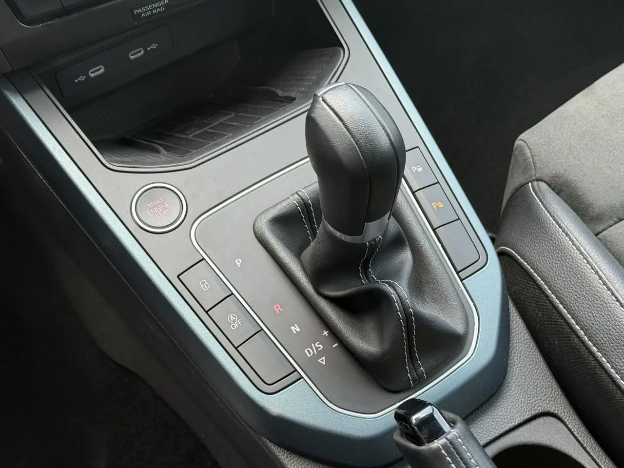 Vue rapprochée de la console centrale du SEAT Arona gris Cliff 2025, mettant en valeur le levier de vitesse automatique et les commandes environnantes.