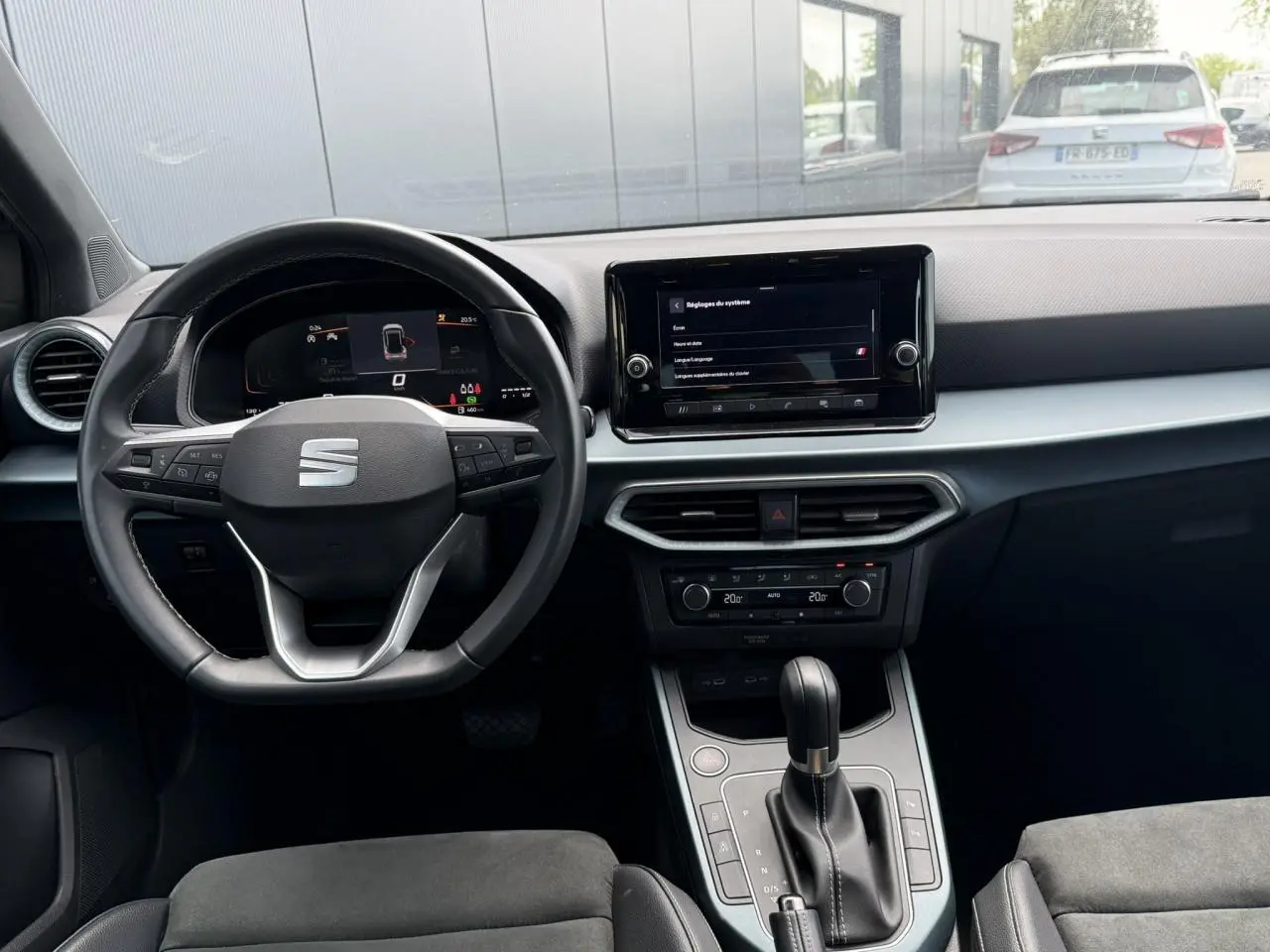 Vue intérieure frontale du poste de conduite du SEAT Arona gris, avec volant multifonction et écran tactile central.