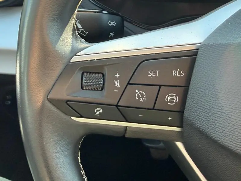 Gros plan sur les commandes multifonctions à gauche du volant cuir du SEAT Arona 2025, boutons de régulateur et assistance.