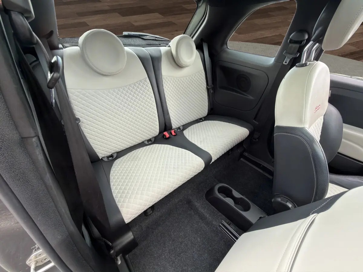 Vue intérieure arrière de la Fiat 500 1.0 gris foncé, sièges arrière et avant en cuir clair matelassé avec logo brodé.