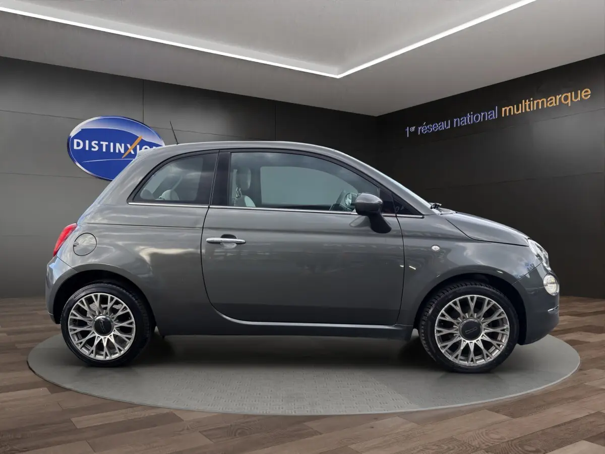 Profil droit de la Fiat 500 gris foncé 2020 avec jantes alliage et rétroviseurs noirs en showroom.