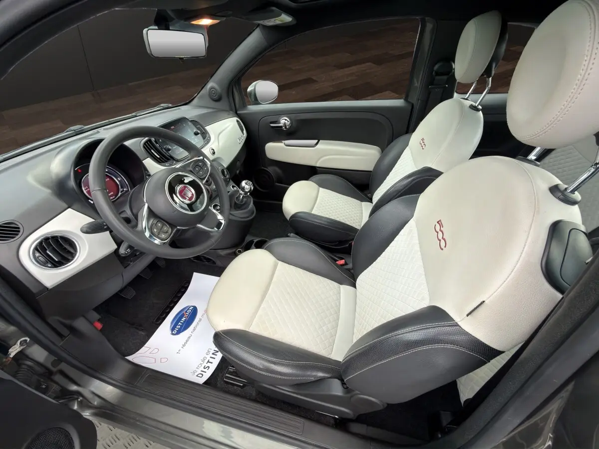 Vue intérieure côté conducteur de la Fiat 500 2020, sièges cuir bicolores beige et noir avec logo 500 brodé.