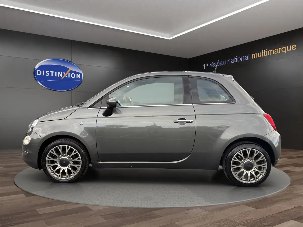 Profil droit d'une FIAT 500 gris foncé 2020 avec jantes alliage au design ajouré dans un showroom.