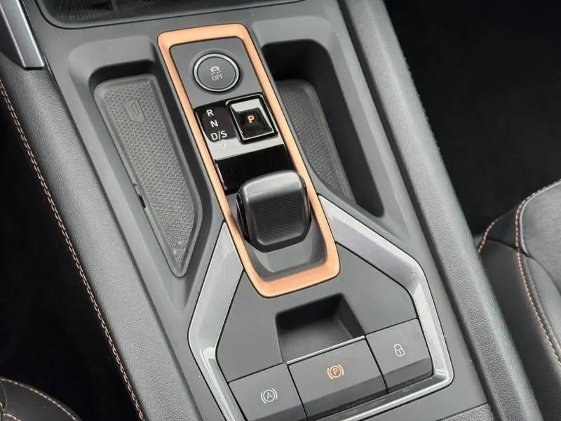 Vue rapprochée de la console centrale du CUPRA Formentor 2025 avec levier de vitesse et cadre cuivre sur fond gris mat.