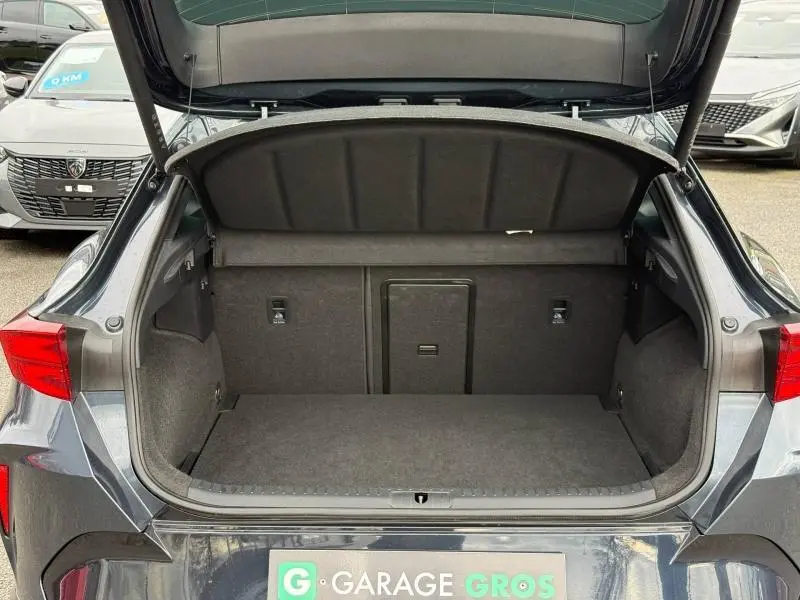 Coffre ouvert vu de l'arrière d'une CUPRA Formentor 1.5 eTSI Hybrid 2025 en Gris Magnétique Mat, intérieur spacieux et tapis gris.