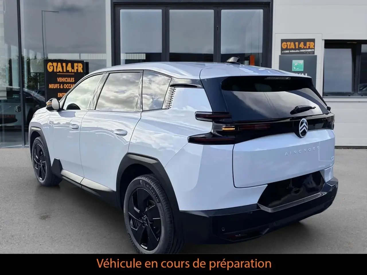 Vue 3/4 arrière droite du Citroën C5 Aircross blanc avec toit noir et jantes noires, stationné devant un bâtiment.