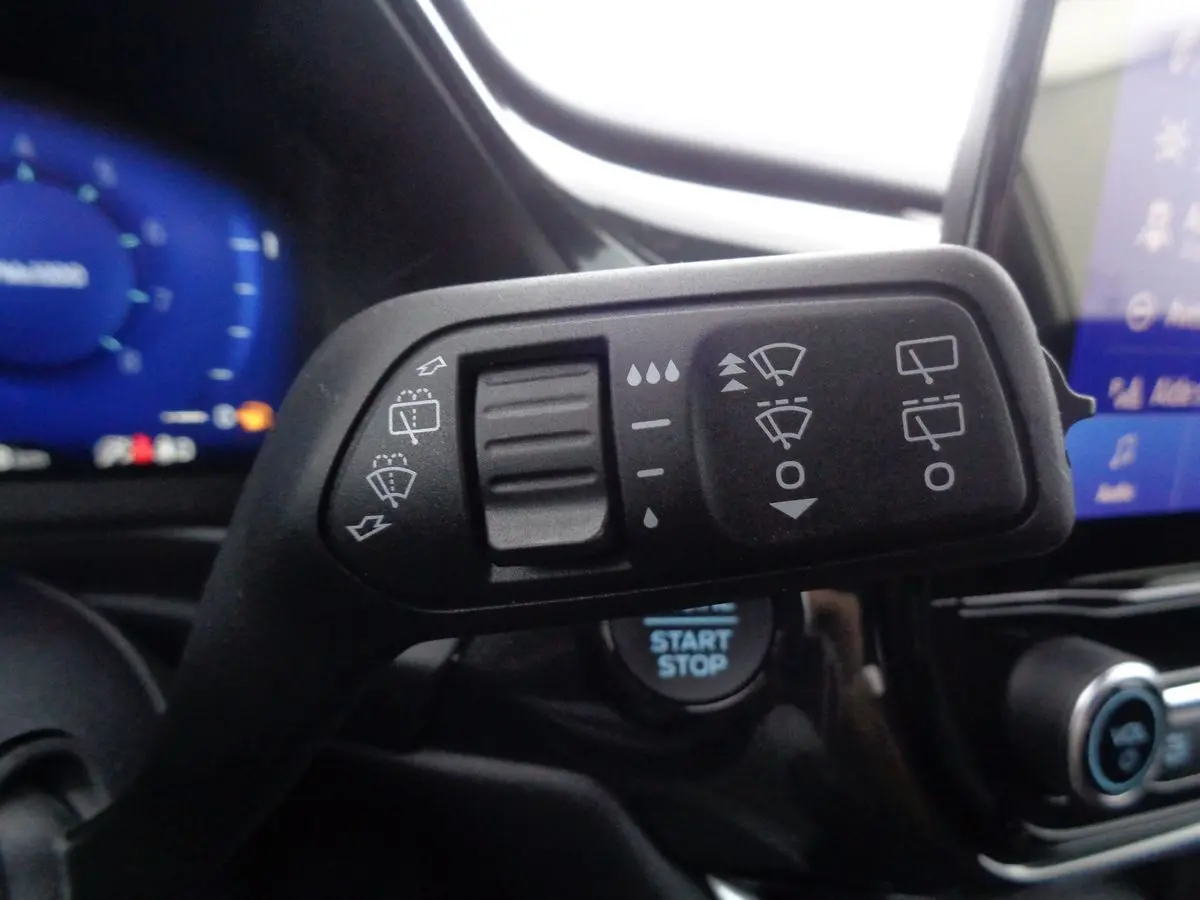 Gros plan sur la commande d’essuie-glace du Ford Puma blanc 2022, avec tableau de bord et bouton start/stop visibles.
