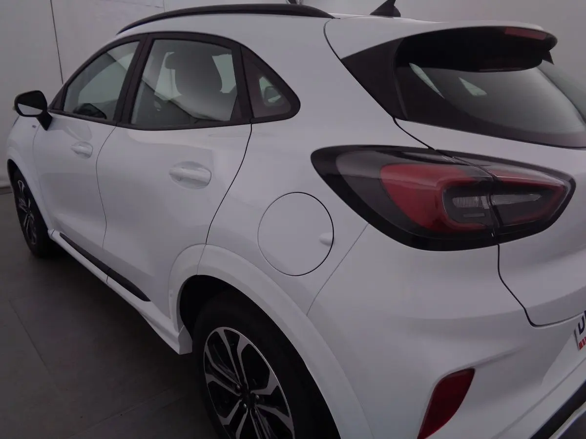 Vue 3/4 arrière droite d'un Ford Puma blanc 2022 finition ST-LINE avec feux arrière LED et jantes bi-ton.