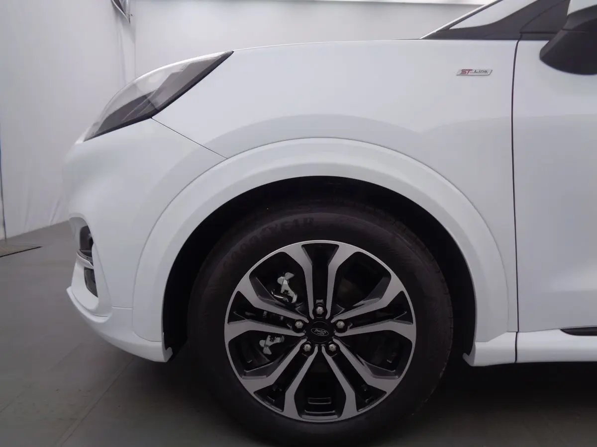 Gros plan sur la roue avant droite et l'aile blanche d'un Ford Puma 1.0 EcoBoost MHEV 2022 finition ST-Line.