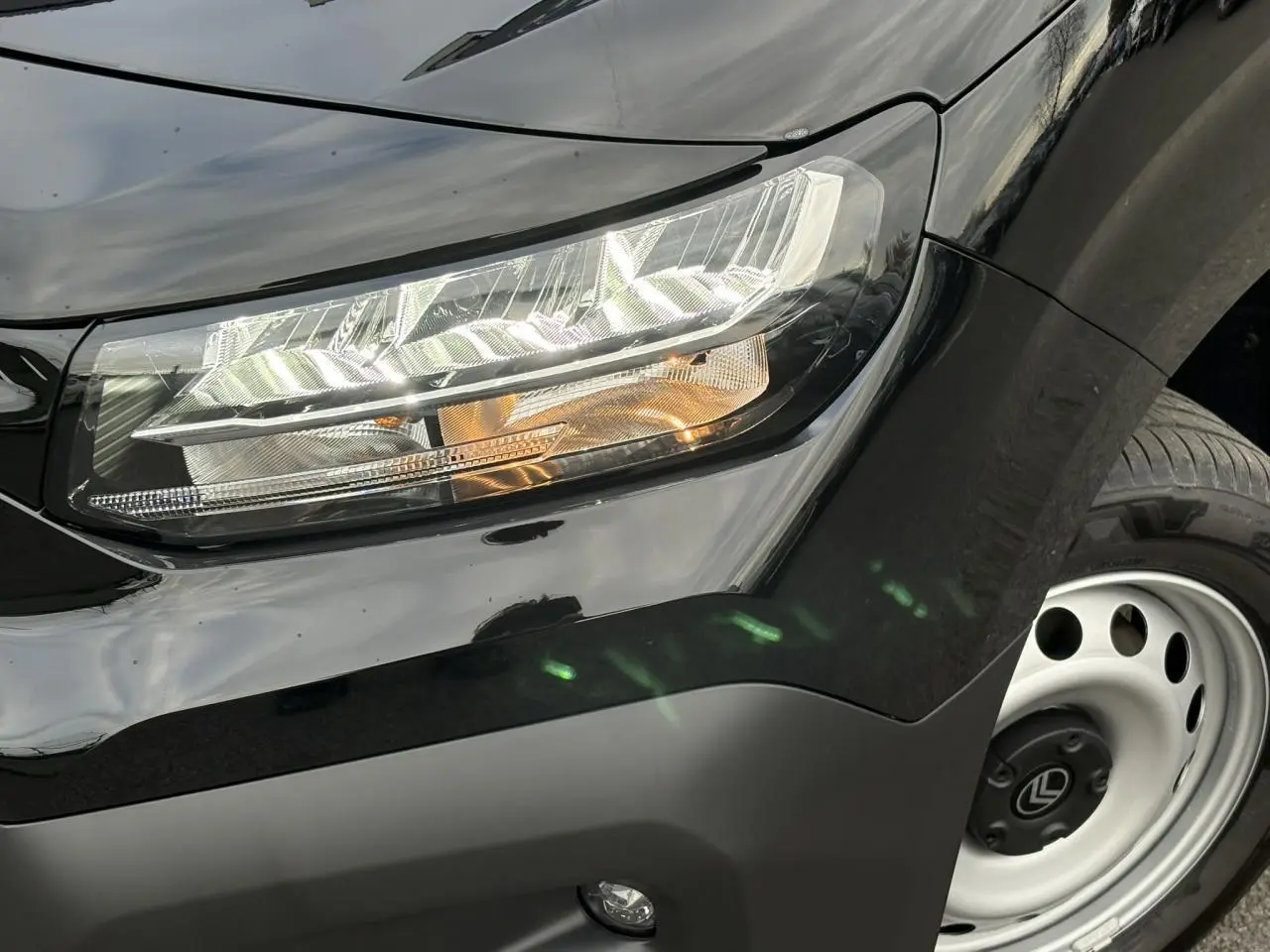 Gros plan sur le phare avant droit et la roue acier du Citroën Berlingo Van XL noir Perla 2025.