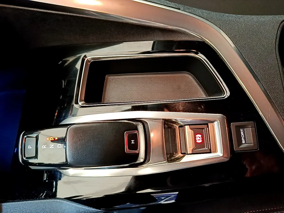 Vue rapprochée de la commande de boîte automatique noire et chrome avec bouton Sport dans un Peugeot 3008 blanc de 2020.