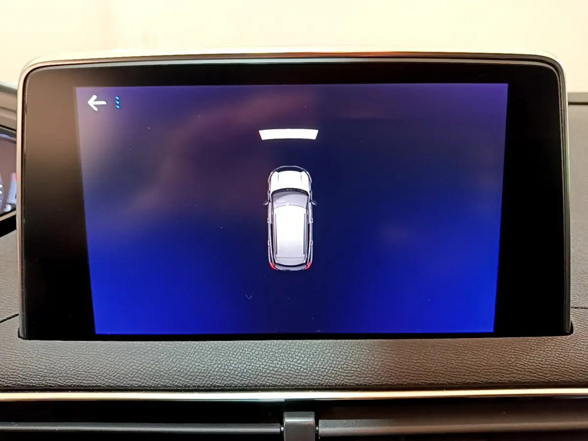 Écran tactile intérieur affichant la vue aérienne du Peugeot 3008 blanc en mode assistance au stationnement.