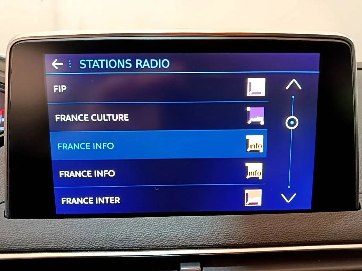 Écran tactile central affichant la sélection des stations radio dans l'habitacle d'un Peugeot 3008 blanc de 2020.