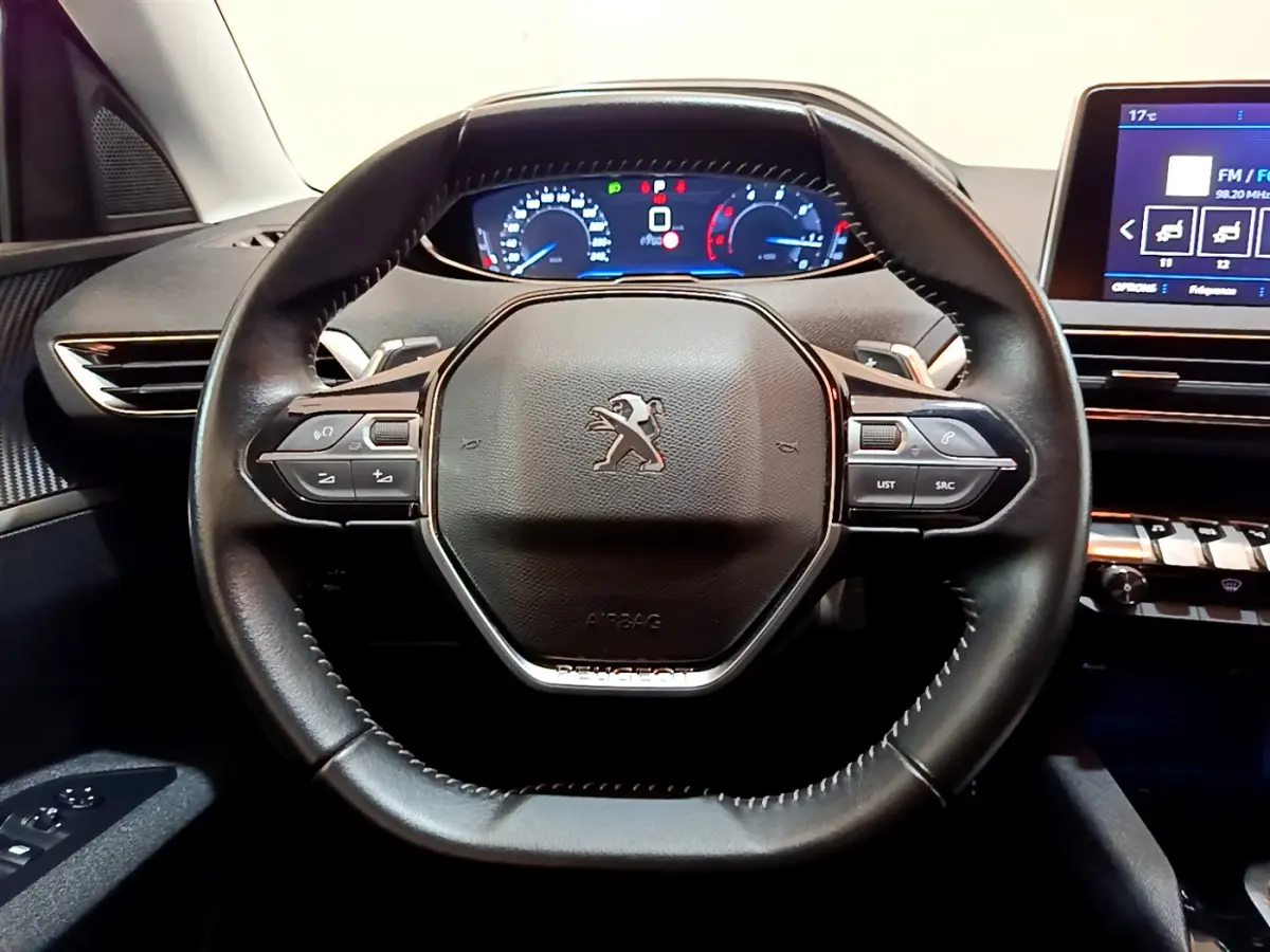 Volant cuir noir avec logo Peugeot, tableau de bord numérique et écran tactile dans l'habitacle du 3008 blanc 2020.