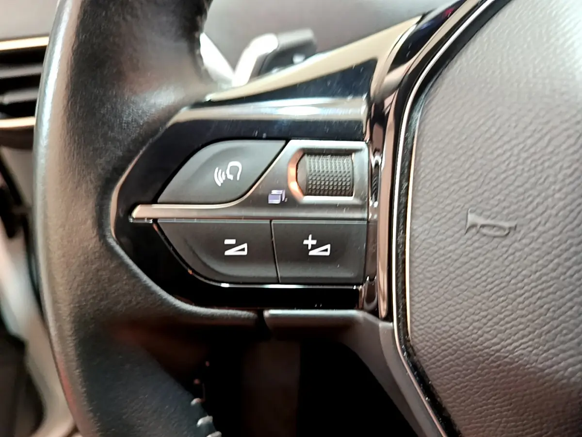 Gros plan sur les commandes de volume et téléphone du volant cuir noir du Peugeot 3008 blanc de 2020.
