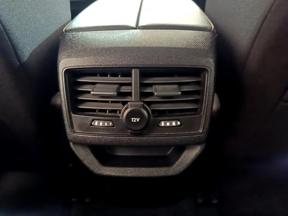 Vue rapprochée des aérateurs arrière noirs et prise 12V intégrée sur la console centrale du Peugeot 3008 blanc 2020.