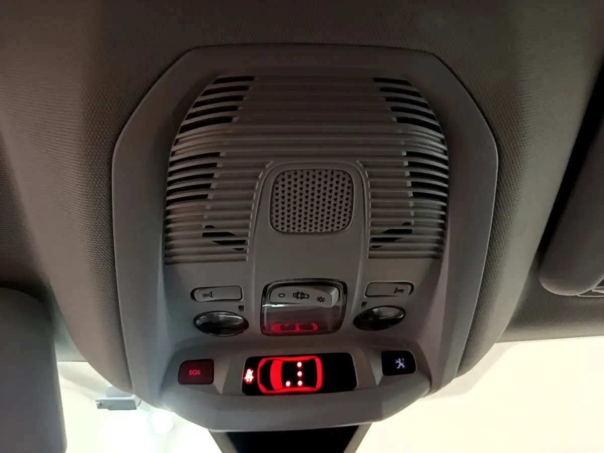 Vue en gros plan du plafonnier intérieur du Peugeot 3008 blanc, avec commandes lumineuses et bouton SOS rouge.